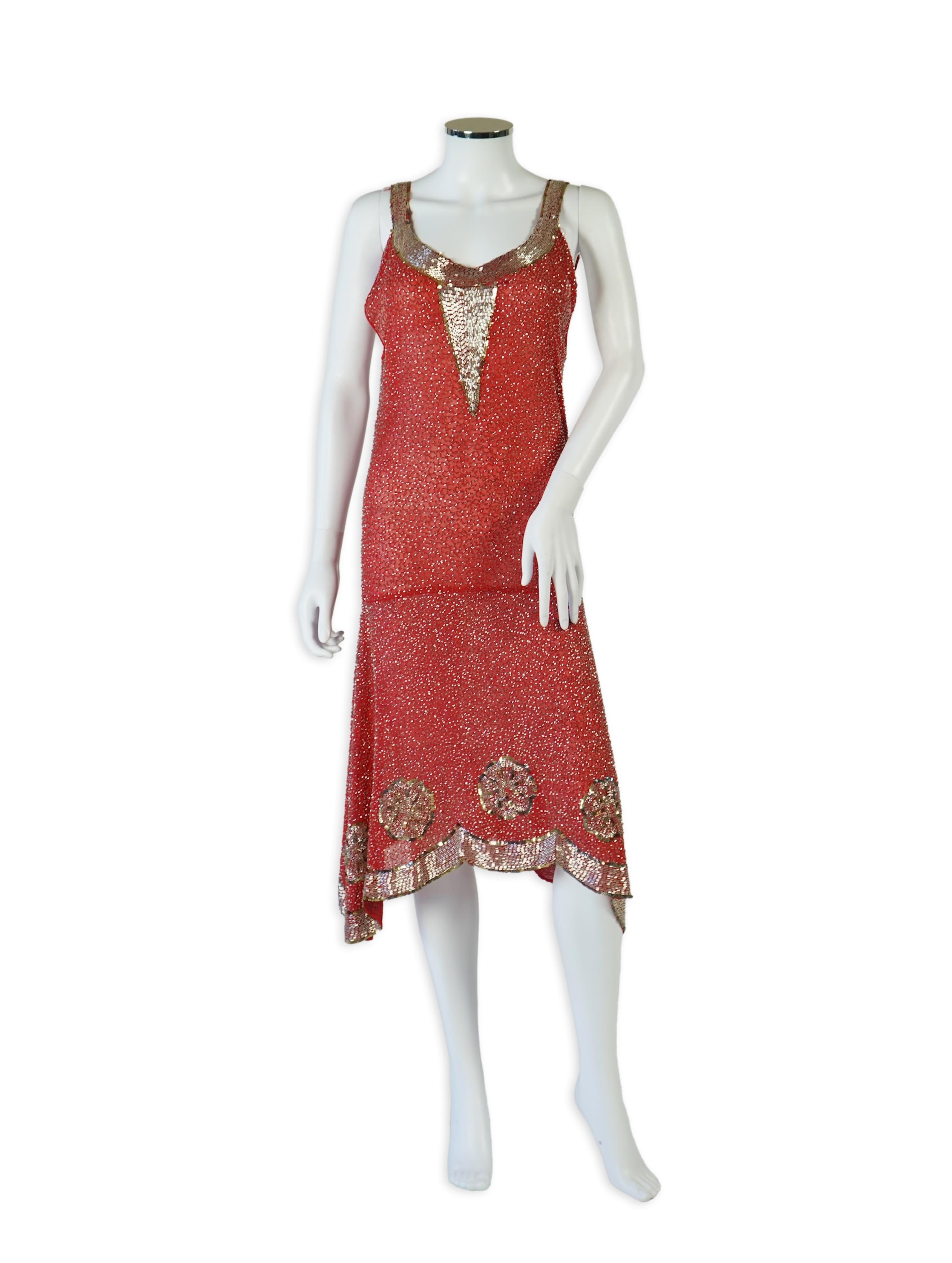 A 1920's red georgette beaded evening dress. Hand beaded and sequinned in white and gold, designed with a dropped waist, handkerchief points and wide beaded border with large stylistic floral motifs. Length 115cm. Condit